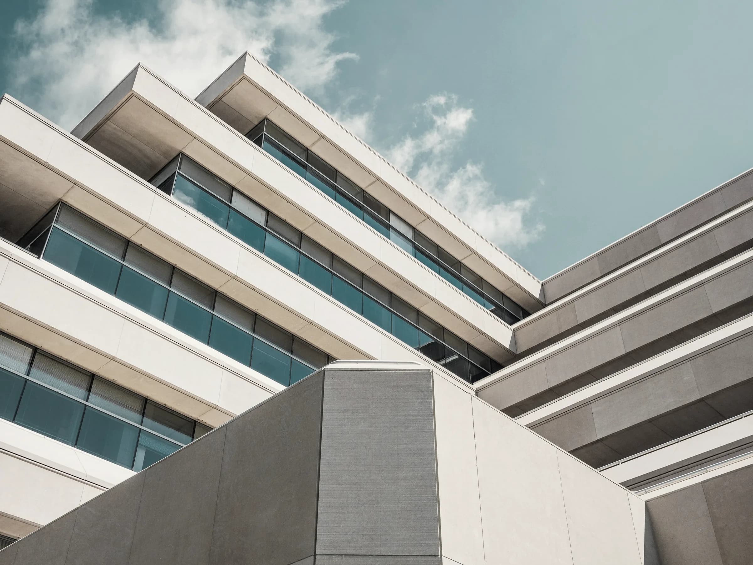 Stacked concrete terraces of a cliffside residence seen from below.